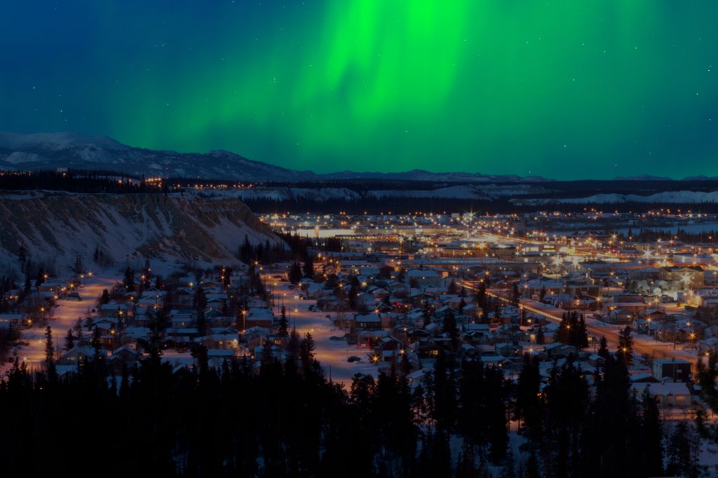Starkes Nordlicht (Aurora borealis) am Nachthimmel über der Innenstadt von Whitehorse, der Hauptstadt des Yukon Territoriums, Kanada, im Winter.