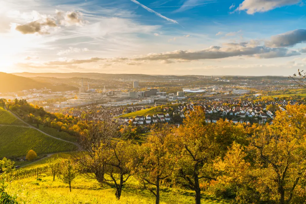 Deutschland, Stuttgart Stadtpanorama Landschaft Blick über Industriehäuser, Straßen, Stadion und Autobahn bei Sonnenuntergang in warmen orangefarbenem Licht